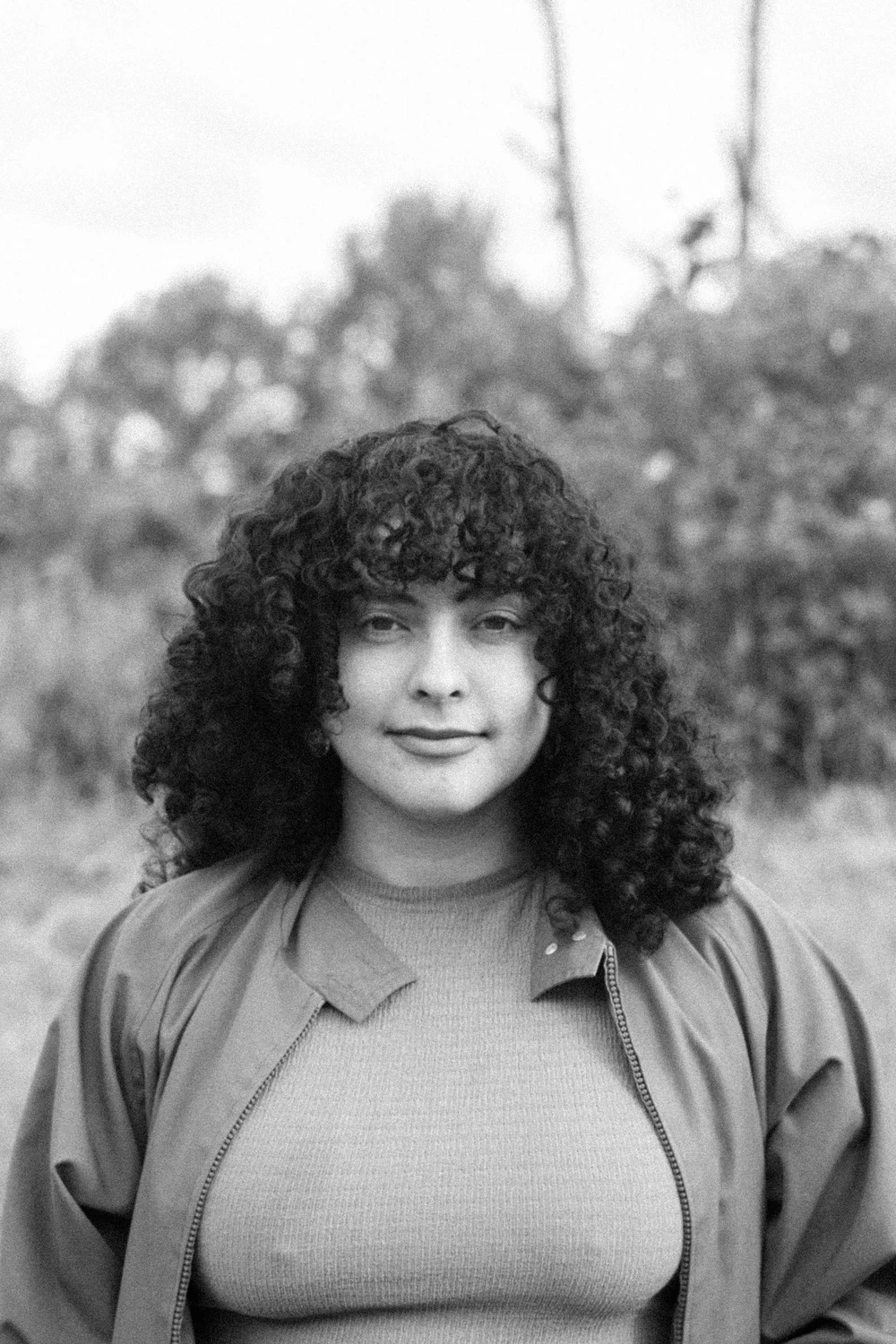 Retrato al aire libre de una integrante de Coocine con cabello rizado, en blanco y negro