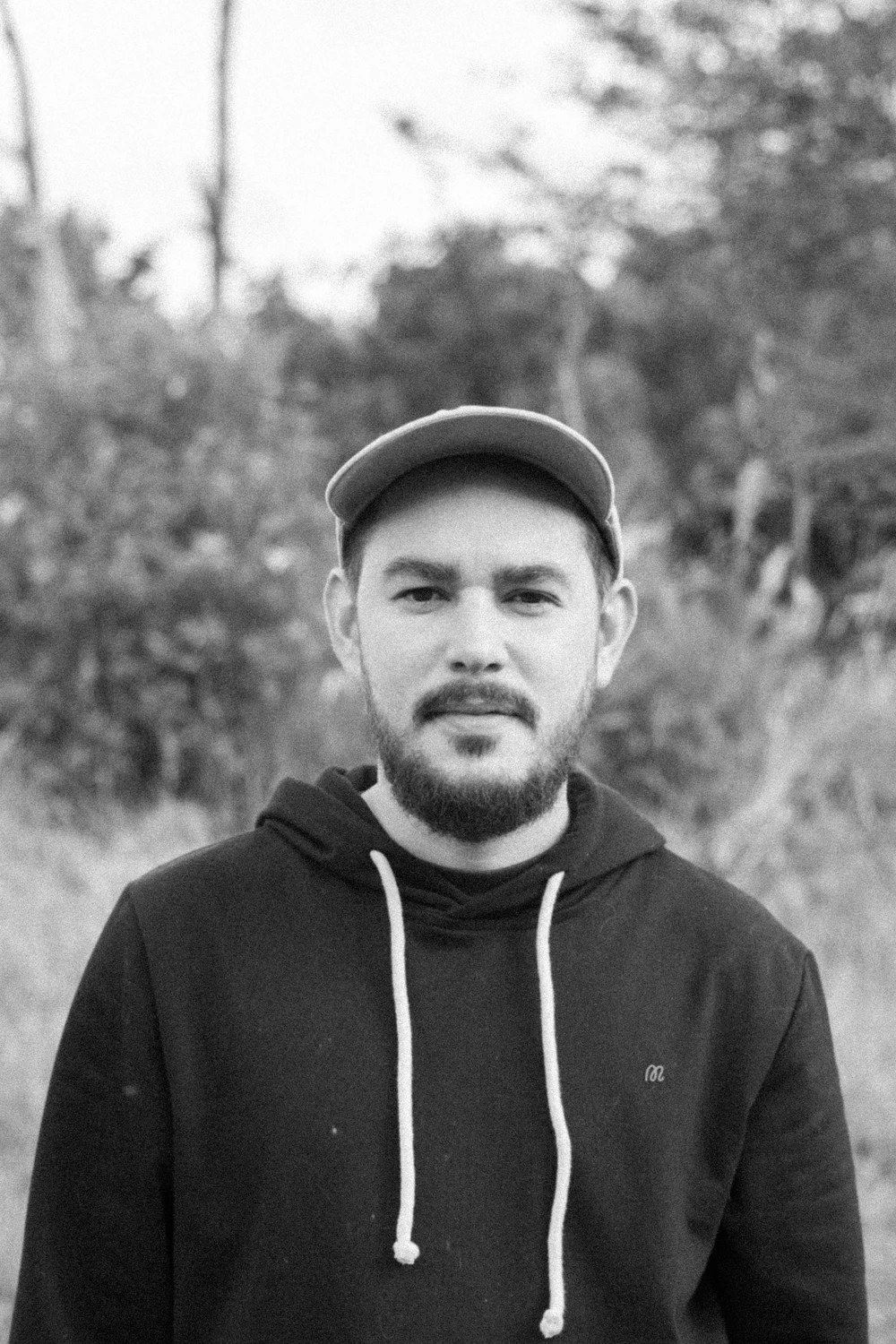 Retrato al aire libre de un integrante de Coocine con gorra, en blanco y negro
