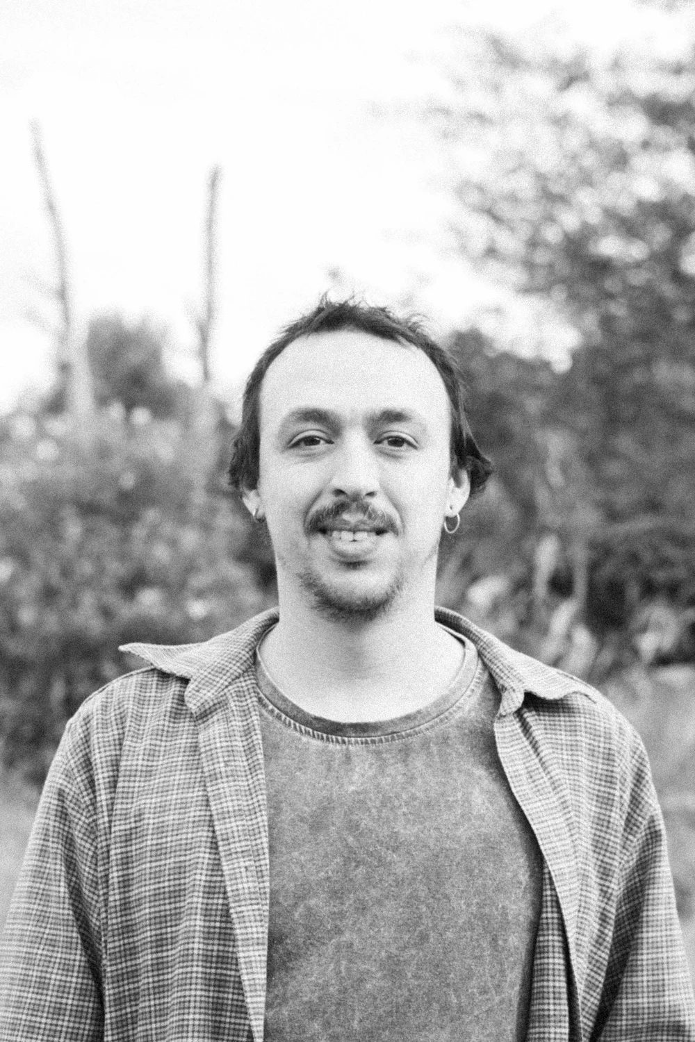 Retrato al aire libre de un integrante de Coocine con camisa a cuadros, en blanco y negro