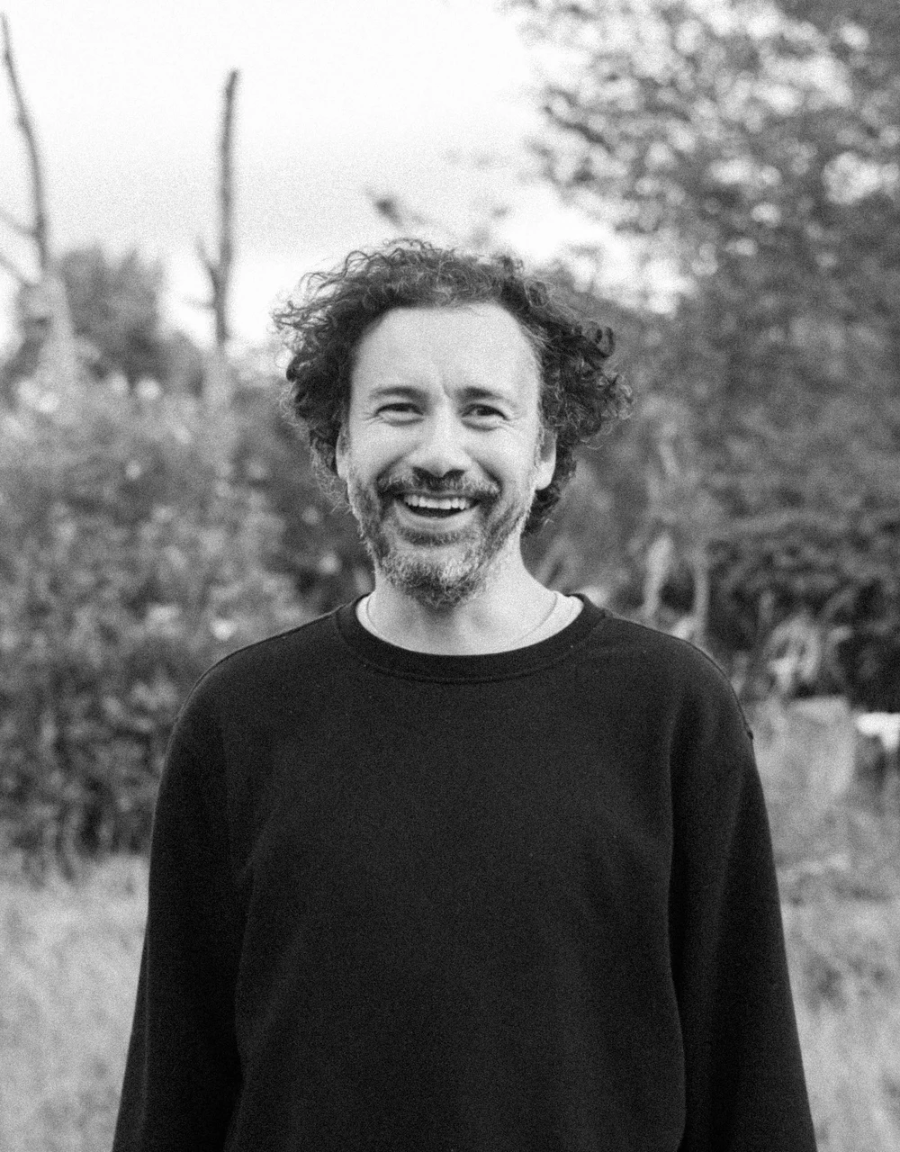 Retrato al aire libre de un integrante de Coocine sonriendo, en blanco y negro