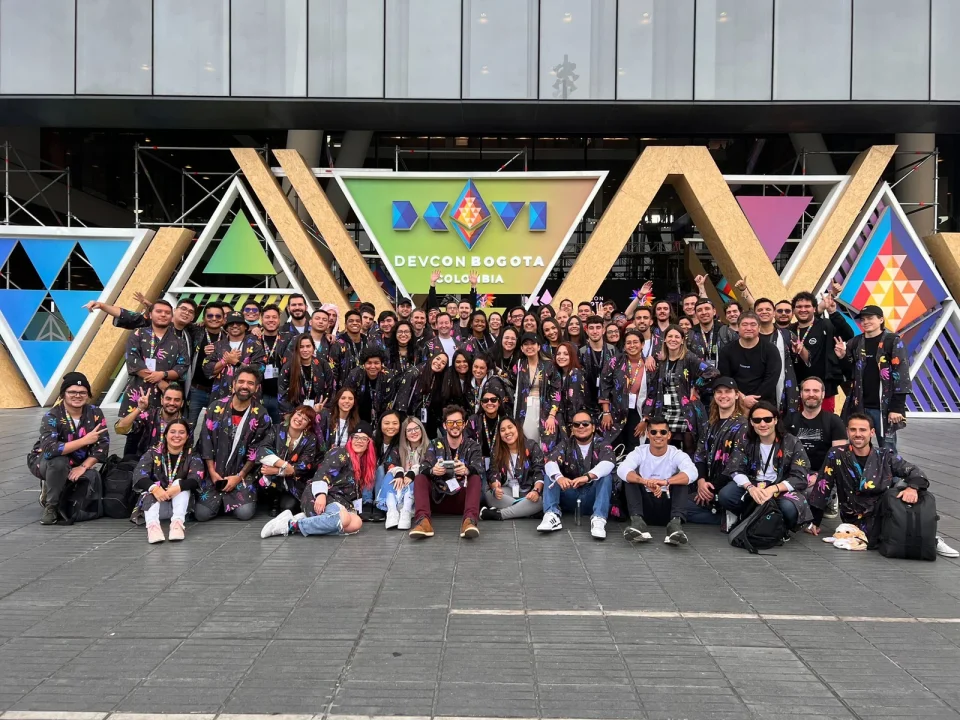 The Reserve team at Devcon Bogotá in front of the Devcon sign, almost everyone wearing the Reserve kimono