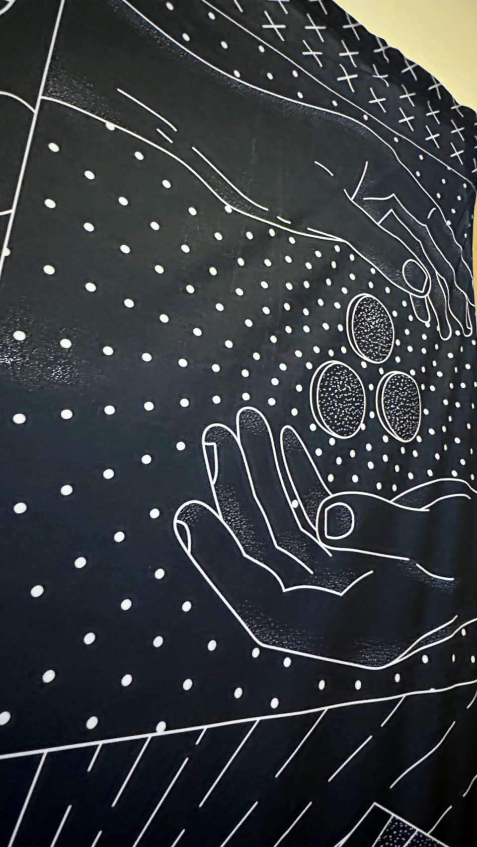 Detail of the printed Monetarium wall: a hand dropping coins into an open hand, in white line on navy